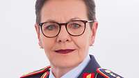 Porträtfoto einer Frau mit vollem kurzem Haarschnitt in blauer Uniform