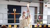 Militärdekan Jonathan Göllner mit der Osterkerze im Hintergrund ein Kreuz