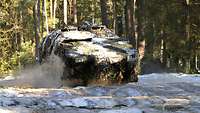 Ein GTK Boxer San Transportpanzer fährt auf einem nassen und welligen Waldweg