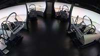 Vier Flug-Simulatoren stehen in einem Raum.