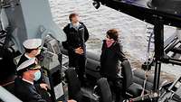 Eine Frau mit kurzen braunen Haaren in dunkelblauer Jacke im Gespräch mit einem Marinesoldaten in blauer Arbeitsuniform. 