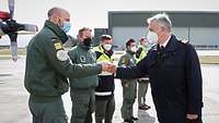 Sechs Soldaten stehen in verschiedenen Uniformen auf einem Flugfeld und begrüßen sich gegenseitig mit Ghettofaust.