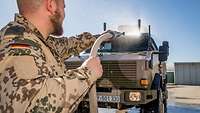 Ein Soldat reinigt mit einem Schlauch ein Fahrzeug vom Typ Dingo