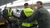 Fünf Soldaten transportieren einen Patienten auf einer Trage durch das Flugzeug A330.