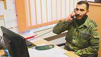 Ein Soldat in Uniform telefoniert in seinem Dienstzimmer. 