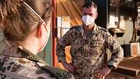 Eine Soldatin spricht mit einem Soldaten. Beide tragen einen Mund-Nasen-Schutz 