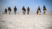 Mehrere Soldaten laufen durch die Wüste