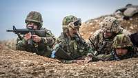 Ein Bundeswehrsoldat übt mit zwei afghanischen Soldaten das Schießen