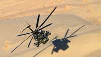 Ein Hubschrauber überfliegt in tiefer Höhe die Wüste