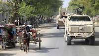 Eine Bundeswehr Kolonne fährt durch eine große Ortschaft durch den afghanischen Straßenverkehr.