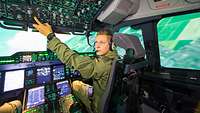 Ein Soldat sitzt in einem Flugzeugsimulator und drückt auf Knöpfe