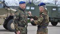 Einem Soldaten wird das Ehrenkreuz der Bundeswehr in Gold an die Feldjacke gesteckt.