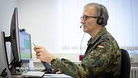 Ein Soldat sitzt vor dem PC und zeigt mit einem Stift auf den Bildschirm während er etwas erklärt