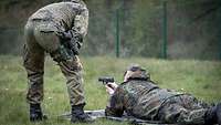 Ein Soldat liegt im Gras und ziehlt mit der P8 in die Ferne.