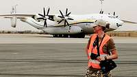 A servicewoman with a camera, standing in front of an aircraft