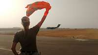 A female waving a safety vest at an aircraft