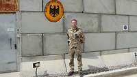 Ein Soldat steht vor einer Mauer. An dieser ist ein Schild mit der Aufschrift „Generalkonsulat BRD" angebracht