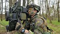 Im Wald schaut ein niederländischer Soldat durch die Optik einer Panzerabwehrwaffe.