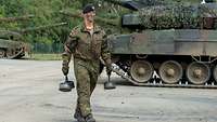 A soldier crossing a storage park. She is carrying three bases from spent shells.