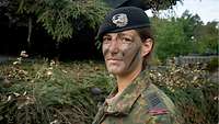 Portrait of a soldier. She is wearing the signature black beret of the armoured forces of the Bundeswehr. 