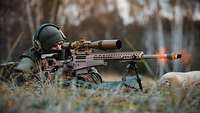 A soldier lies behind his weapon and fires.