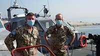 Zwei Soldaten mit Mund-Nasen-Schutz stehen auf einem Marineschiff 