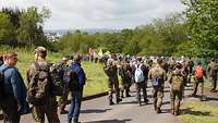 Eine Gruppe von knapp 80 Menschen läuft auf einer geteerten Straße, im Hintergrund ist Eifelpanorama zu sehen