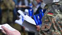 Soldaten bei einer Andacht während einer regionalen Lourdwallfahrt mit einer blauen Lourdesfackel in der Hand