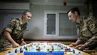 Zwei Soldaten spielen konzentriert an einem Tischkicker