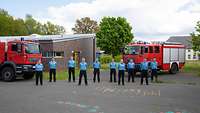 Gruppenbild mit zehn Personen in Uniformen der Feuerwehr vor zwei Löschfahrzeugen.