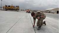 Ein Soldat kniet auf einem Rollfeld eines Flugplatzes