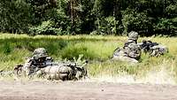 Zwei Soldaten liegen mit ihren Gewehren in verschiedenen Richtungen in Stellung.