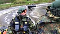 Gruppen von Soldaten fahren mit ihren Schlauchbooten eine große Kehre auf einem Fluss.