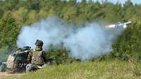 Ein Panzerabwehrsystem wird aus einer Stellung abgeschossen. Im Bild sind der Schweif und Rauch zu sehen.