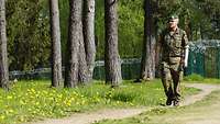 Ein Soldat läuft einen Waldweg entlang