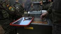 Soldatinnen und Soldaten stehen um eine mit Eintopf gefüllte Therme, aus der mit einer Schöpfkelle Essen ausgegeben wird