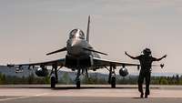 Ein Soldat weist einen Eurofighter in seine Parkposition ein.