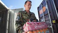 Soldat trägt Getränke aus Container
