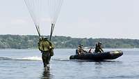 Ein Soldat landet am Fallschirm hängend im Schwielowsee. Im Hintergrund ist ein Speedboot mit zwei Soldaten