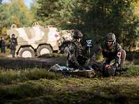 Two soldiers care for a wounded man during an exercise