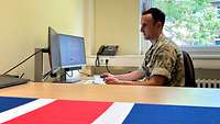 Ein britischer Soldat sitzt in seinem Büro mit einer britischen Flagge.