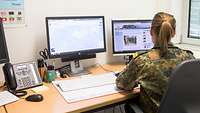 Soldatin mit dem Rücken zur Kamera arbeitet an einem PC.