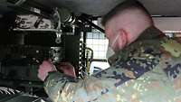 Ein Soldat baut ein Funkgerät in ein Fahrzeug ein.