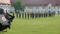 Musiker des Gebirgsmusikkorps stehen auf einer Wiese in der Gäuboden-Kaserne