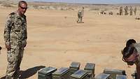 Ein Soldat steht auf einem Sprengplatz in der Wüste. Vor ihm stehen einige Munitionskisten der US-Streitkräfte