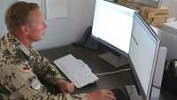 Ein Soldat sitzt an einem Schreibtisch vor einem Computer. Er bearbeitet seine Munitionsmaßnahmen mittels einer Software