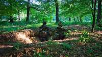 Zwei Soldaten sind Alarmposten. Sie sichern das Gelände in einer ausgehobenen kleinen Grube im Wald
