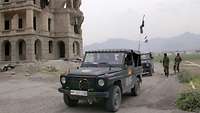 Deutsche Soldaten fahren im Geländewagen Wolf durch Kabul, im Hintergrund der Kings Palace