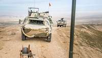 Ein Transportpanzer Fuchs fährt auf einer unbefestigten Straße durch eine Wüstenlandschaft, hinter ihm fährt ein AFT Dingo