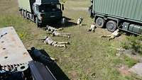 Soldaten liegen mit ihren Waffen auf dem Boden in Deckung ihrer Fahrzeug